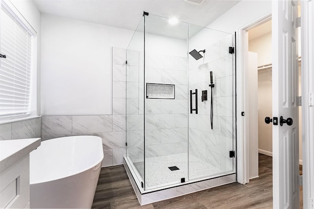21511 Pepperberry Trl, Spring, TX 77388 - full bathroom with a freestanding tub, wood finished floors, a shower stall, a walk in closet, and tile walls