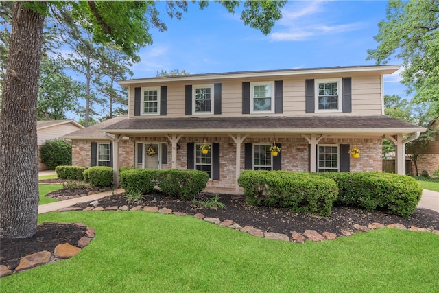 8223 Bairnsdale Ln, Houston, TX 77070 - colonial-style house with a front yard, covered porch, brick siding, and a shingled roof
