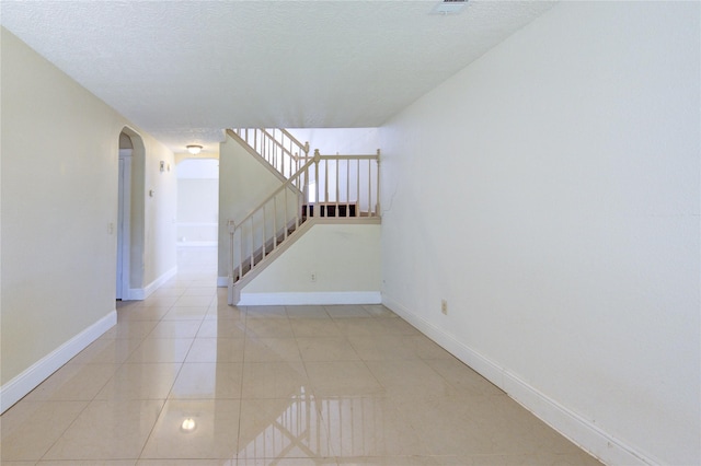 2815 Lakefield Way, Sugar Land, TX 77479 - spare room with arched walkways, baseboards, light tile patterned floors, stairway, and a textured ceiling