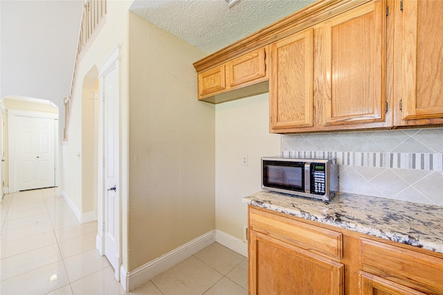 2815 Lakefield Way, Sugar Land, TX 77479 - kitchen with stainless steel microwave, light tile patterned floors, tasteful backsplash, light stone counters, and baseboards