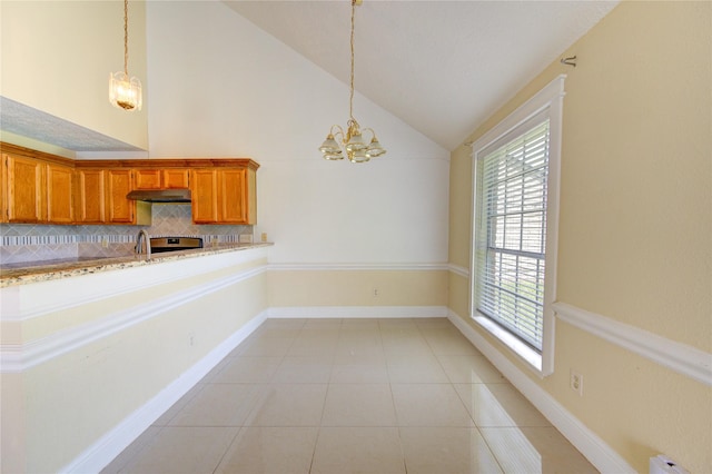 2815 Lakefield Way, Sugar Land, TX 77479 - kitchen with under cabinet range hood, vaulted ceiling, backsplash, a chandelier, and brown cabinetry