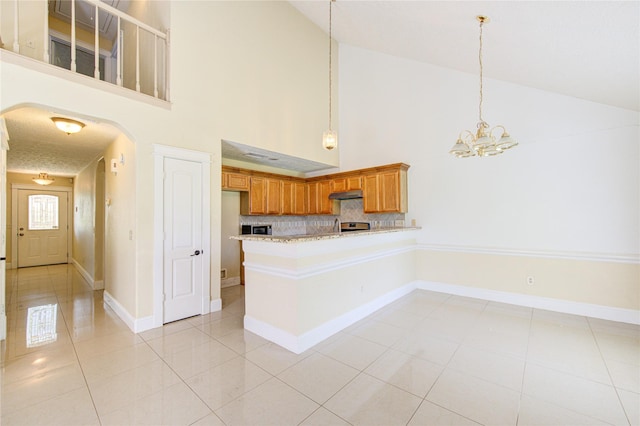 2815 Lakefield Way, Sugar Land, TX 77479 - kitchen with high vaulted ceiling, arched walkways, a chandelier, brown cabinets, and light tile patterned floors
