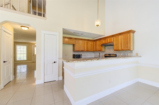 2815 Lakefield Way, Sugar Land, TX 77479 - kitchen featuring a towering ceiling, stainless steel appliances, backsplash, light tile patterned flooring, and a peninsula
