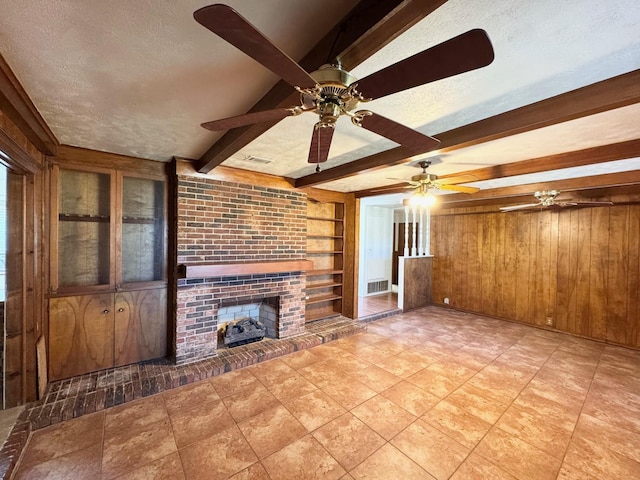 121 Briar Ln, Crockett, TX 75835 - unfurnished living room with beam ceiling, wood walls, a ceiling fan, a fireplace, and a textured ceiling