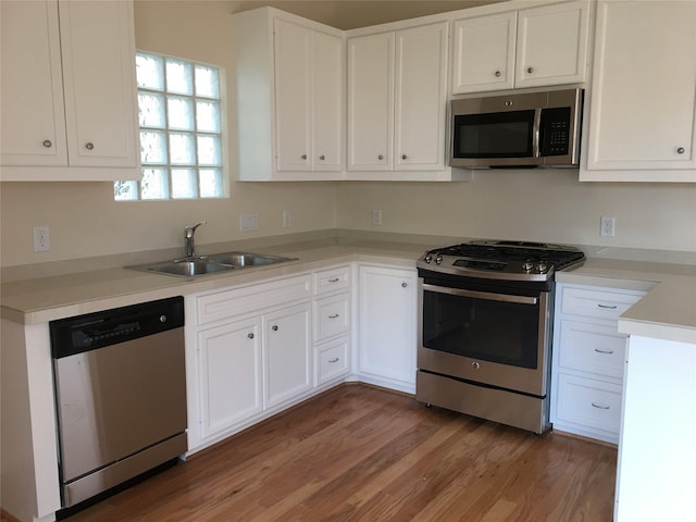 3727 Main Poplar Dr, Houston, TX 77025 - kitchen featuring stainless steel appliances, a sink, light wood-style flooring, and white cabinets