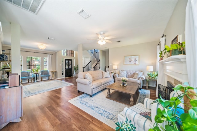 living room with stairs, a fireplace, wood finished floors, and ceiling fan