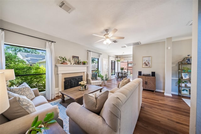 living area with wood finished floors, ceiling fan, a fireplace, and baseboards