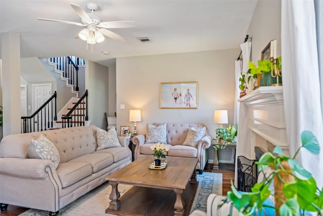 living area featuring ceiling fan, stairway, wood finished floors, and a fireplace