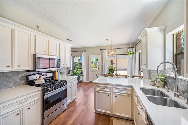 kitchen with stainless steel appliances, a sink, a chandelier, light countertops, and a textured ceiling