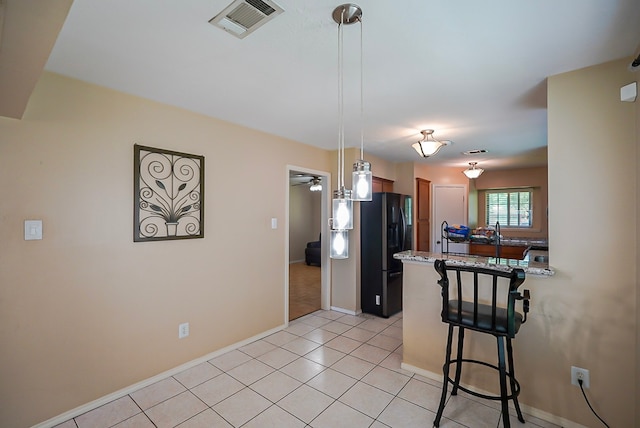 18907 Oak Bower Dr, Humble, TX 77346 - kitchen with a breakfast bar, black refrigerator with ice dispenser, a peninsula, baseboards, and pendant lighting