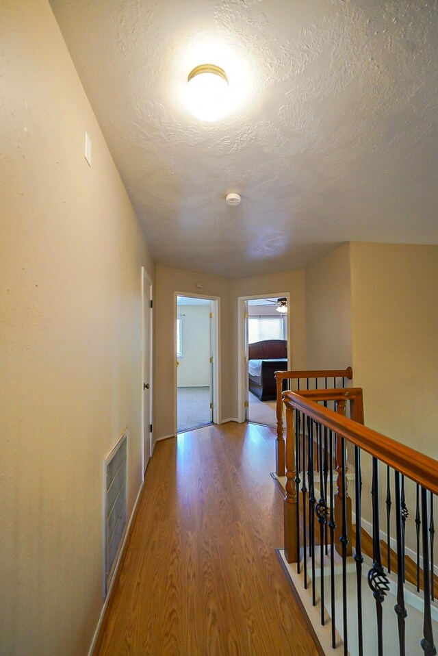 18907 Oak Bower Dr, Humble, TX 77346 - hallway with wood finished floors, an upstairs landing, a textured ceiling, and baseboards
