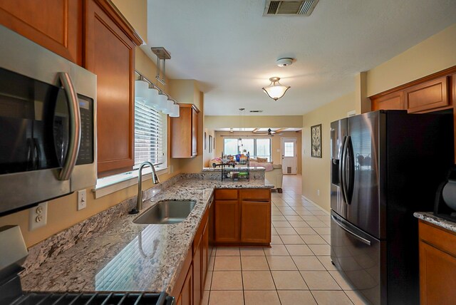 18907 Oak Bower Dr, Humble, TX 77346 - kitchen featuring appliances with stainless steel finishes, a sink, a peninsula, and brown cabinetry