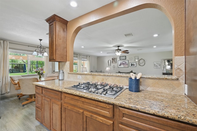 13111 Oak Plaza Dr, Cypress, TX 77429 - kitchen with arched walkways, stainless steel gas stovetop, light wood finished floors, tasteful backsplash, and recessed lighting