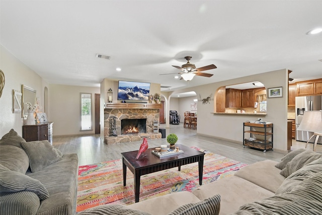13111 Oak Plaza Dr, Cypress, TX 77429 - living room with arched walkways, a ceiling fan, light wood-style floors, a fireplace, and recessed lighting