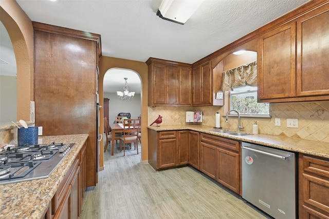 13111 Oak Plaza Dr, Cypress, TX 77429 - kitchen with stainless steel appliances, a sink, arched walkways, and light wood-type flooring