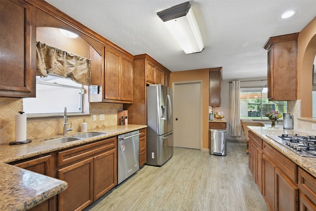 13111 Oak Plaza Dr, Cypress, TX 77429 - kitchen with appliances with stainless steel finishes, a sink, light wood-style flooring, backsplash, and brown cabinets