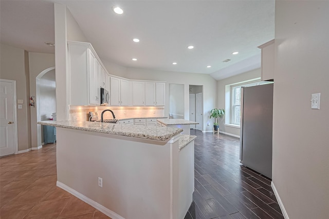 21122 Lilac Meadows Ln, Richmond, TX 77407 - kitchen with stainless steel appliances, arched walkways, white cabinets, baseboards, and recessed lighting