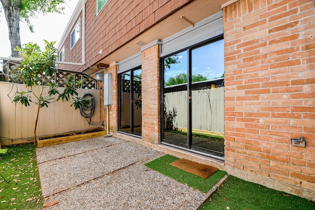 500 N Post Oak Ln, Houston, TX 77024 - view of exterior entry with brick siding, fence, mansard roof, and a patio