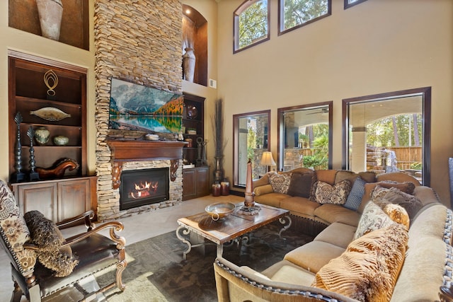 living room with healthy amount of natural light, a high ceiling, a stone fireplace, and built in features