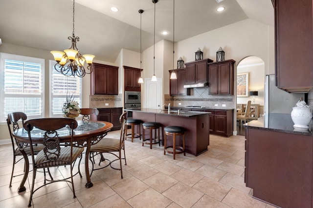 18 Homed Lark Pl, Spring, TX 77389 - kitchen featuring stainless steel appliances, under cabinet range hood, arched walkways, a chandelier, and a center island with sink
