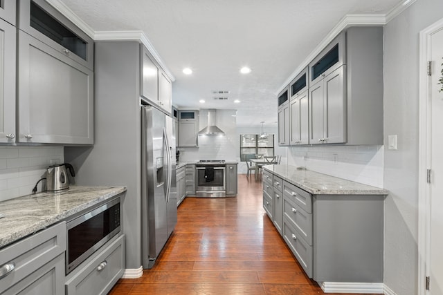 22338 Prince George St, Katy, TX 77449 - kitchen with gray cabinetry, appliances with stainless steel finishes, wall chimney exhaust hood, backsplash, and dark wood-type flooring