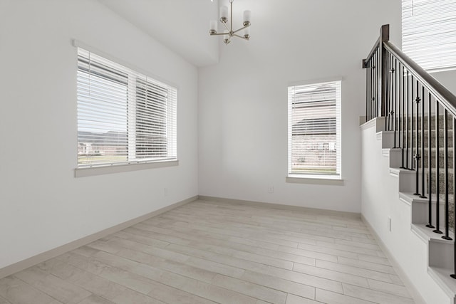 unfurnished room featuring a chandelier, stairway, light wood-type flooring, and baseboards