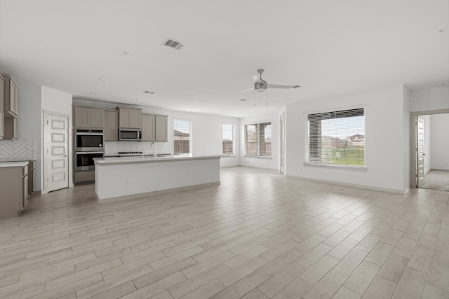 unfurnished living room featuring ceiling fan, baseboards, and light wood-style flooring