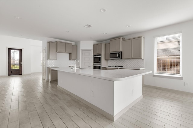kitchen with appliances with stainless steel finishes, gray cabinetry, a sink, decorative backsplash, and recessed lighting