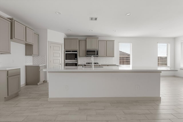 kitchen with stainless steel appliances, gray cabinetry, a spacious island, backsplash, and recessed lighting