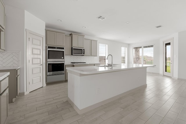 kitchen featuring appliances with stainless steel finishes, gray cabinetry, a sink, decorative backsplash, and recessed lighting