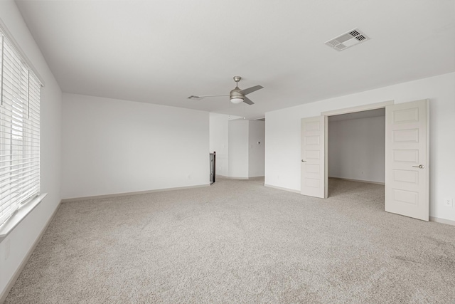 unfurnished bedroom featuring light carpet, multiple windows, ceiling fan, and baseboards