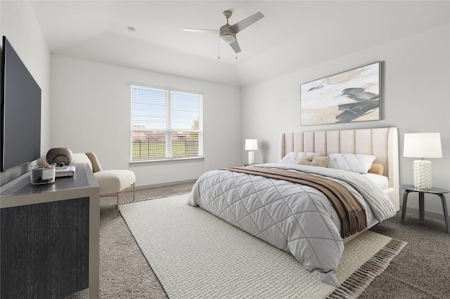 carpeted bedroom with a raised ceiling, ceiling fan, and baseboards