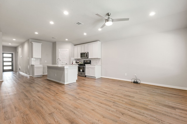 7438 Victoria Brook Trce, Richmond, TX 77407 - kitchen with appliances with stainless steel finishes, open floor plan, backsplash, a center island with sink, and light wood-type flooring