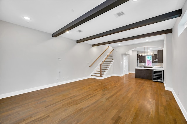 1215 W 23rd St, Houston, TX 77008 - unfurnished living room featuring wood finished floors, arched walkways, baseboards, beverage cooler, and beamed ceiling