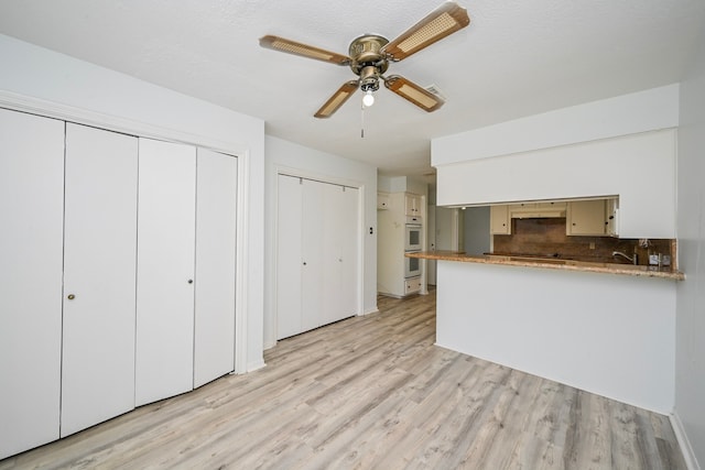 7735 Quail Meadow Dr, Houston, TX 77071 - kitchen with light wood finished floors, decorative backsplash, ceiling fan, a peninsula, and black electric stovetop