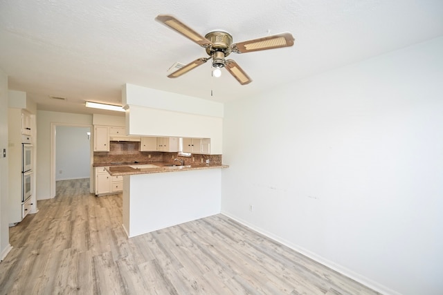 7735 Quail Meadow Dr, Houston, TX 77071 - kitchen featuring a peninsula, decorative backsplash, ceiling fan, light wood-style flooring, and double oven
