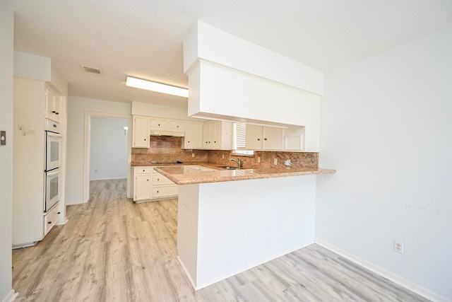 7735 Quail Meadow Dr, Houston, TX 77071 - kitchen featuring a peninsula, light wood finished floors, tasteful backsplash, and white double oven