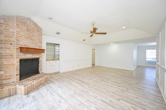 7735 Quail Meadow Dr, Houston, TX 77071 - unfurnished living room with vaulted ceiling, a brick fireplace, light wood finished floors, ceiling fan, and a textured ceiling