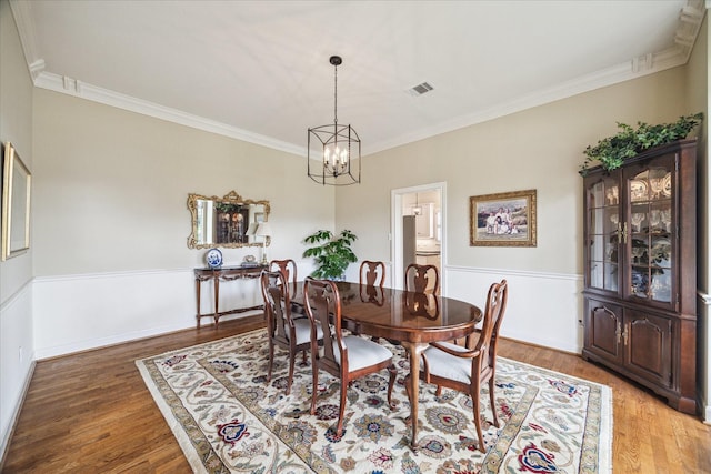 51 Dartmoor Ct, Sugar Land, TX 77479 - dining area with ornamental molding, a chandelier, light wood-style floors, and a wainscoted wall