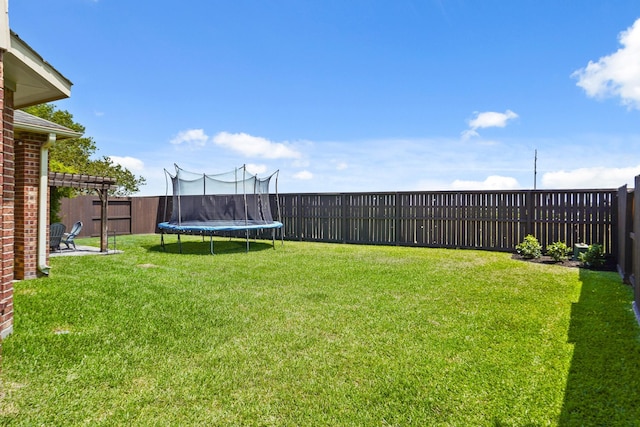 view of yard featuring a trampoline and a pergola