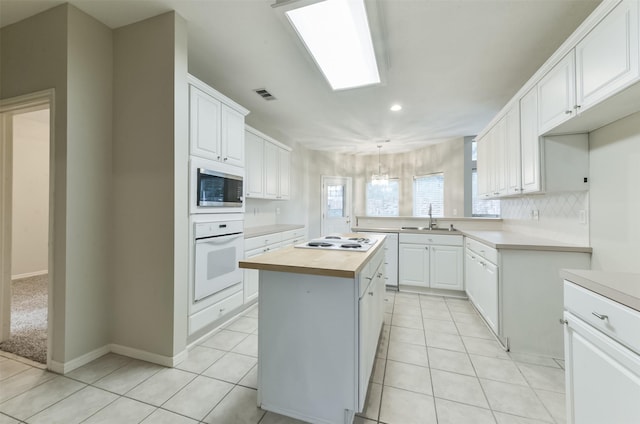 12950 Quail Park Dr, Cypress, TX 77429 - kitchen with white appliances, a sink, wooden counters, white cabinets, and recessed lighting