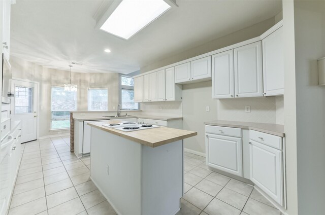 12950 Quail Park Dr, Cypress, TX 77429 - kitchen featuring white electric cooktop, a kitchen island, light tile patterned floors, white cabinetry, and recessed lighting