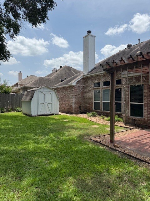 12950 Quail Park Dr, Cypress, TX 77429 - back of property with a storage shed, a chimney, a patio area, and brick siding