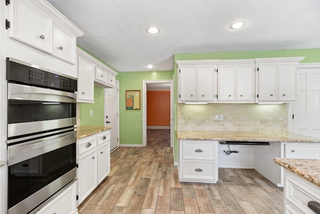 12923 Hunterfield Dr, Cypress, TX 77429 - kitchen featuring stainless steel double oven, white cabinetry, light wood finished floors, decorative backsplash, and baseboards