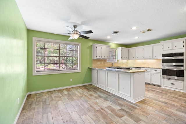 12923 Hunterfield Dr, Cypress, TX 77429 - kitchen featuring appliances with stainless steel finishes, white cabinetry, a peninsula, a ceiling fan, and baseboards