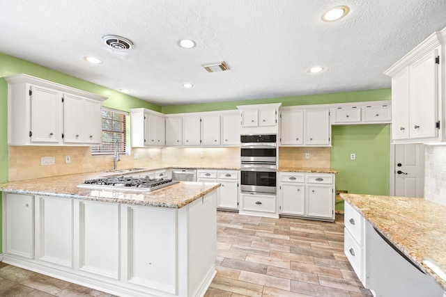 12923 Hunterfield Dr, Cypress, TX 77429 - kitchen featuring stainless steel appliances, a sink, white cabinets, a peninsula, and a textured ceiling