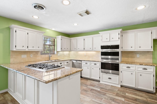 12923 Hunterfield Dr, Cypress, TX 77429 - kitchen with appliances with stainless steel finishes, white cabinets, a peninsula, a sink, and recessed lighting
