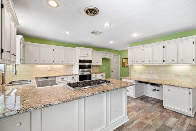 12923 Hunterfield Dr, Cypress, TX 77429 - kitchen with stainless steel appliances, a sink, a peninsula, white cabinetry, and recessed lighting