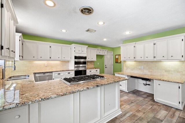12923 Hunterfield Dr, Cypress, TX 77429 - kitchen featuring appliances with stainless steel finishes, a sink, a peninsula, white cabinets, and recessed lighting