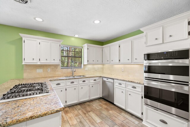 12923 Hunterfield Dr, Cypress, TX 77429 - kitchen featuring a sink, appliances with stainless steel finishes, white cabinets, recessed lighting, and a textured ceiling
